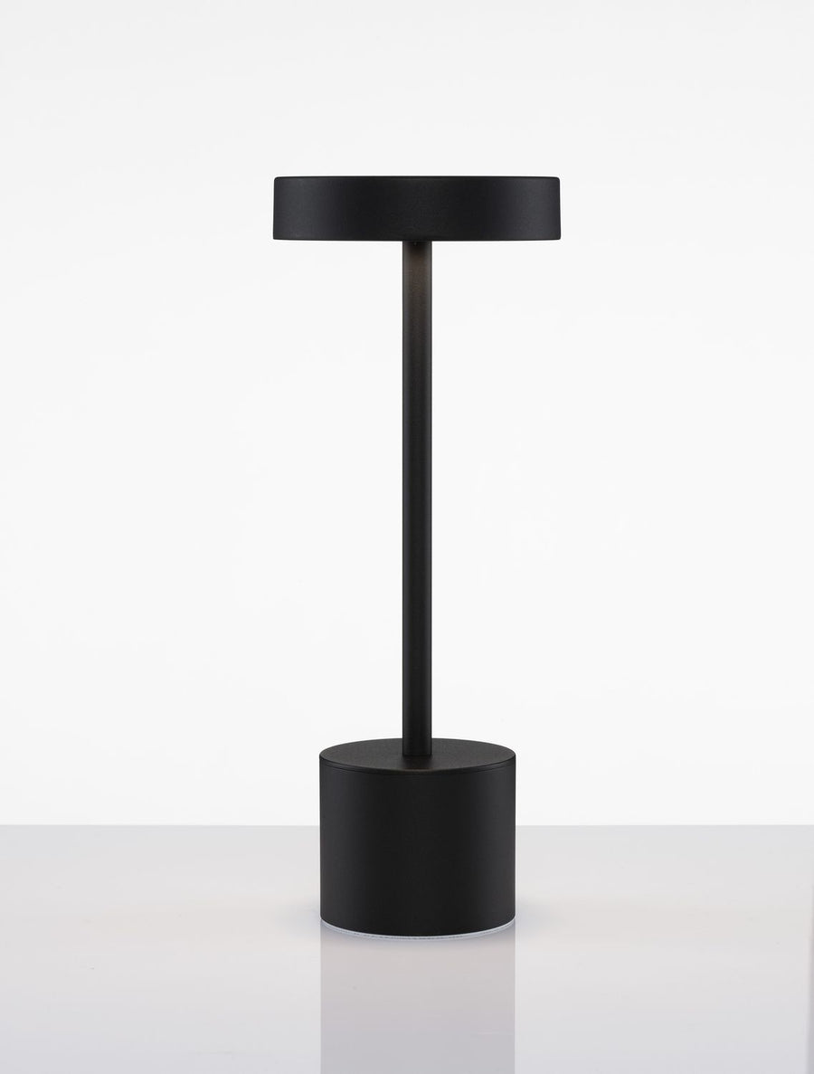 Produit noir présenté de face, socle rond et pied vertical sur surface réfléchissante.