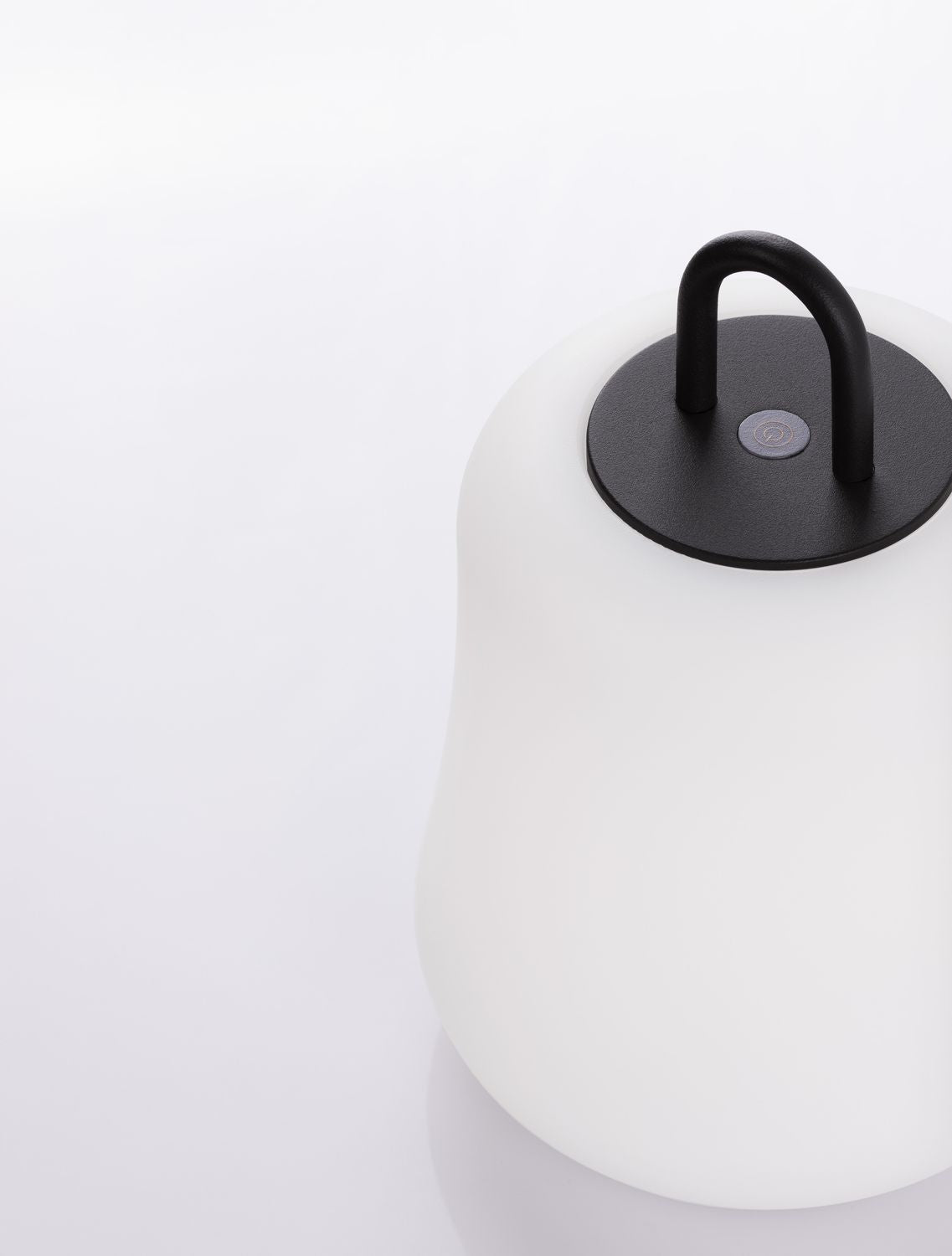 Gros plan sur le bouton tactile et l'anse noire du luminaire.