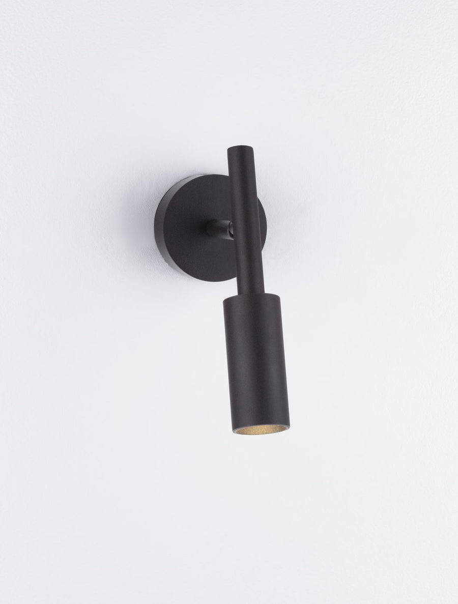 Détail du bas de l'applique noire laissant apparaître l'ampoule dorée à l'intérieur