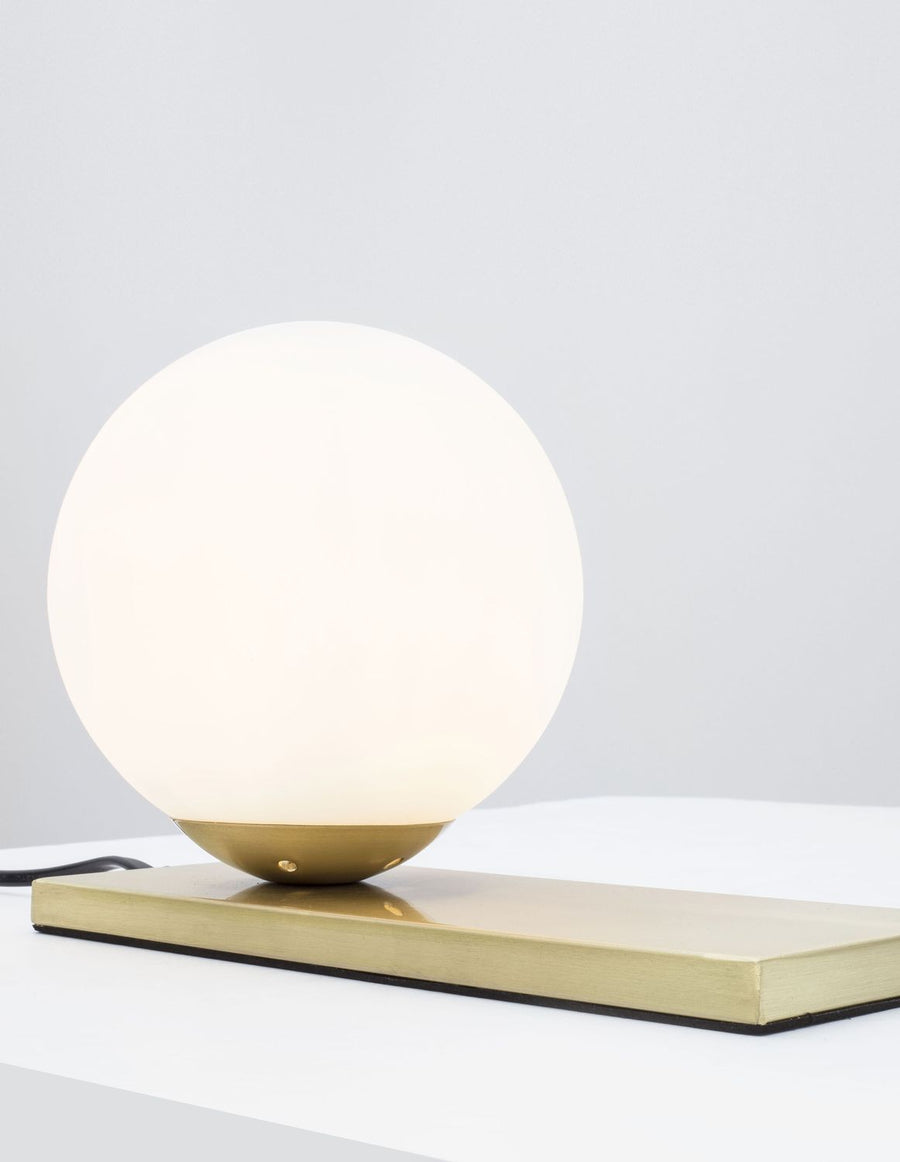 Lampe à poser avec globe de verre opalin blanc sur socle doré, vue de face
