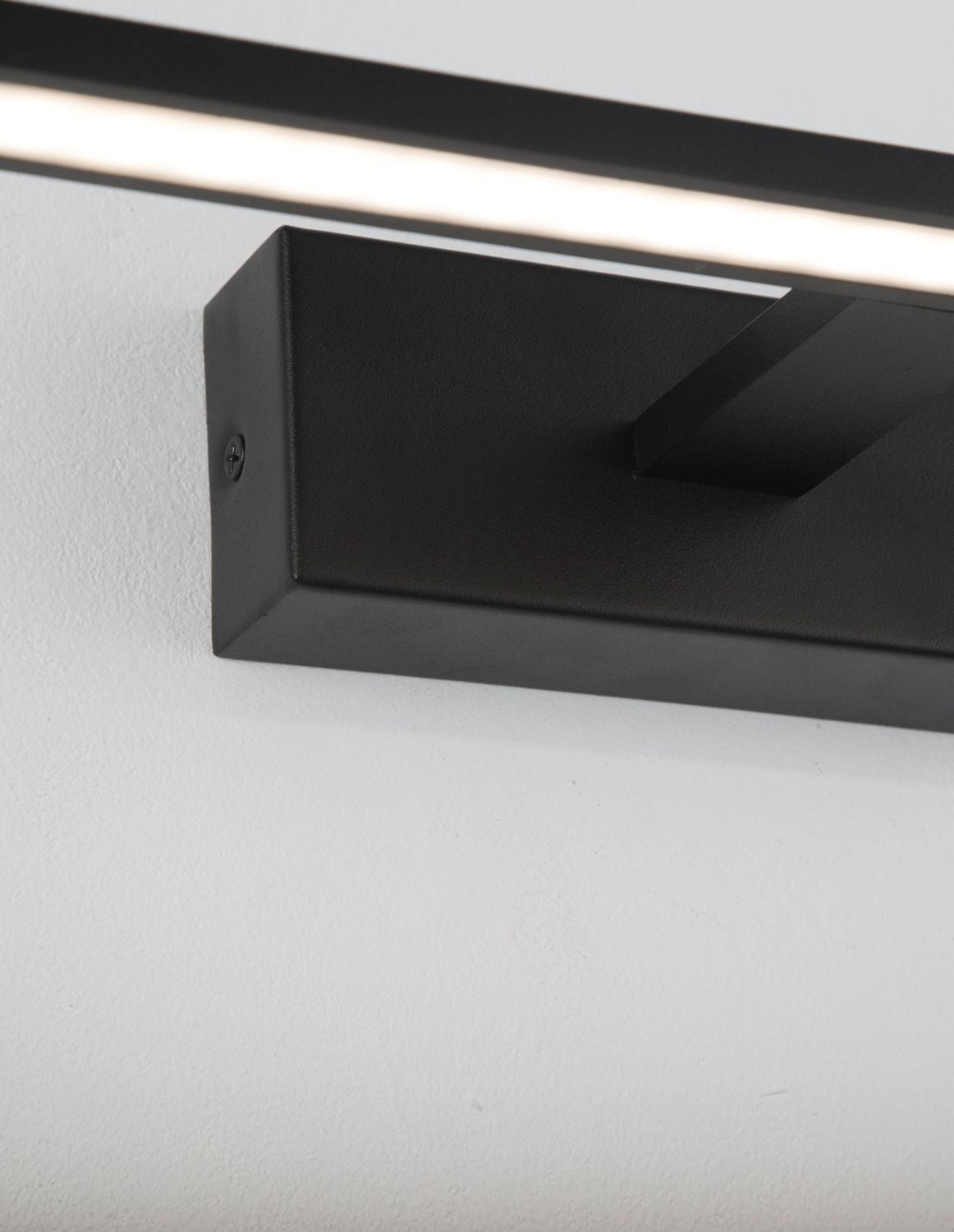 Détail du boîtier de fixation noir et de sa vis, finition mate épurée.