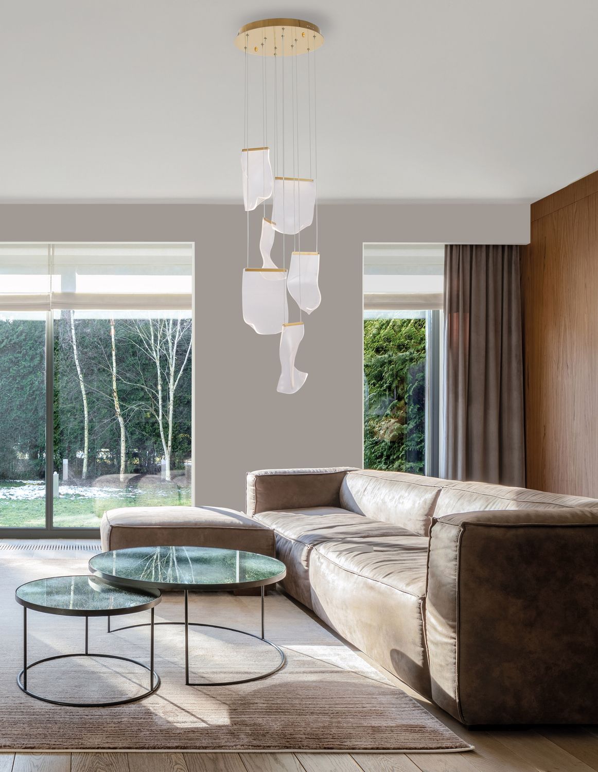 Suspension dorée allumée dans un salon moderne, au-dessus d'un canapé en cuir