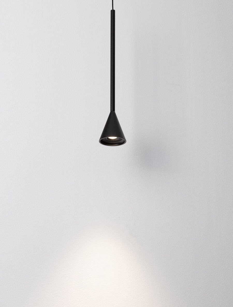 Détail de l'abat-jour conique noir allumé, lumière chaude vers le bas