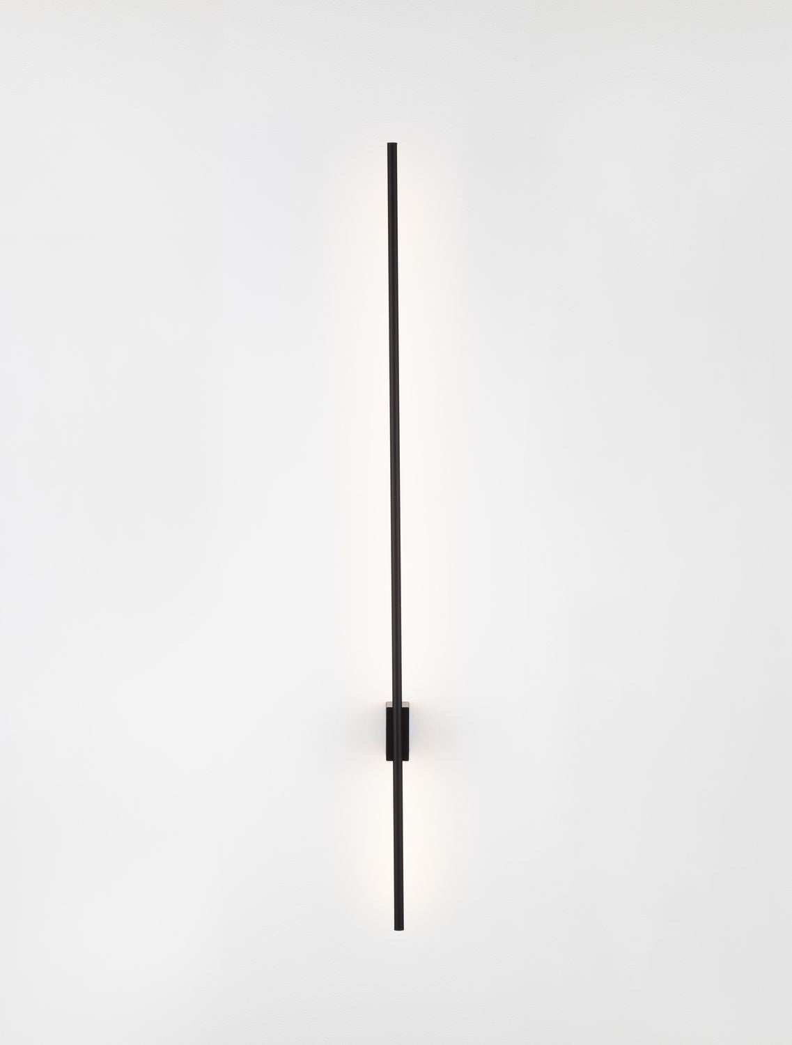 Produit allumé, lumière rasante éclairant le mur en dégradé chaud.