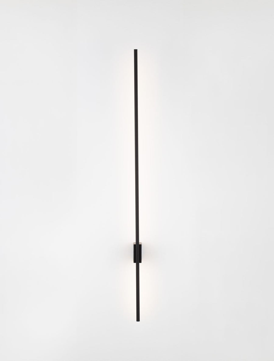 Produit allumé, lumière rasante éclairant le mur en dégradé chaud.