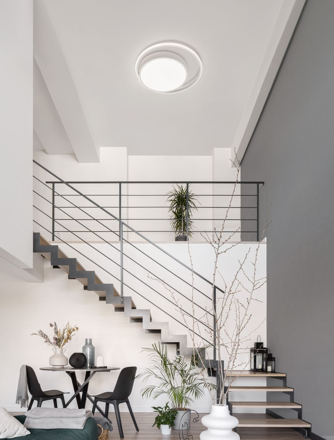 Vue d'ambiance montrant le plafonnier blanc allumé au plafond dans un intérieur moderne.