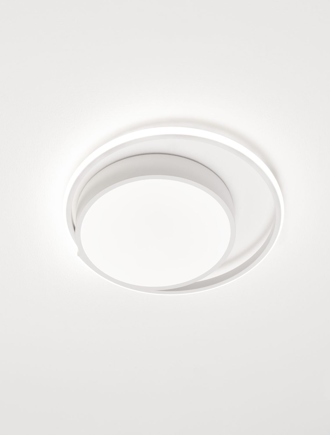 Plafonnier blanc en fonctionnement diffusant une lumière douce au plafond.