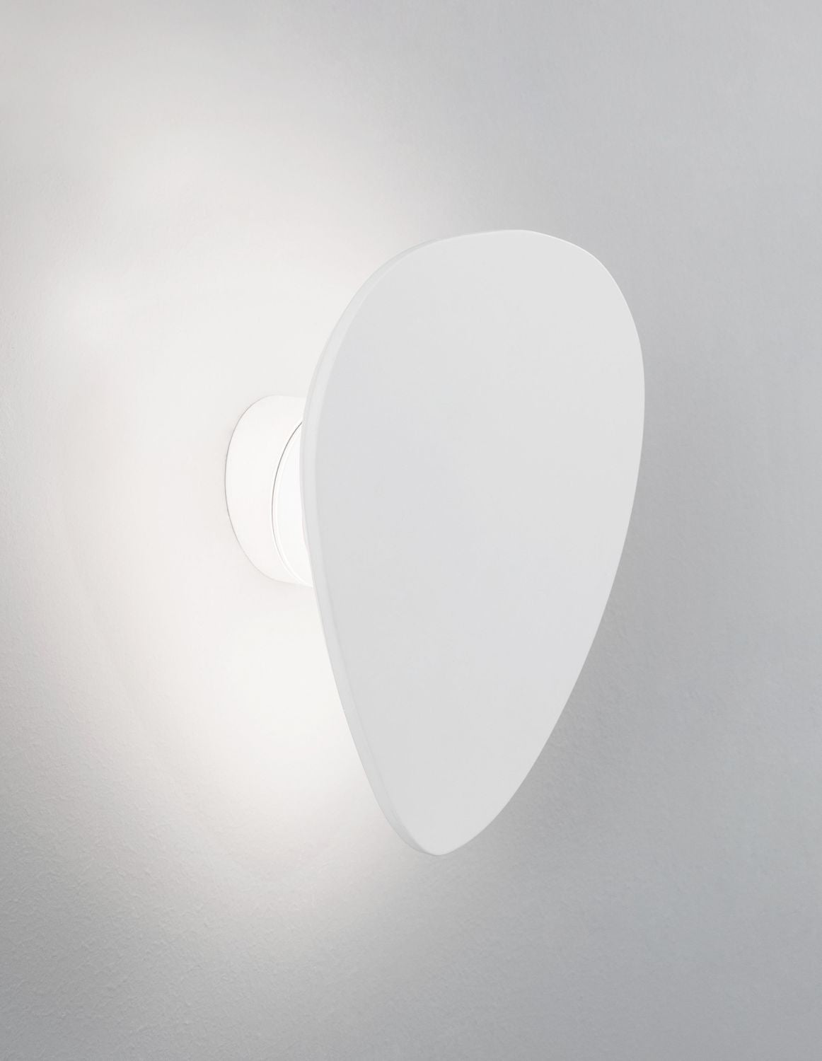 Gros plan d'un module en plâtre blanc diffusant un halo lumineux doux sur le mur