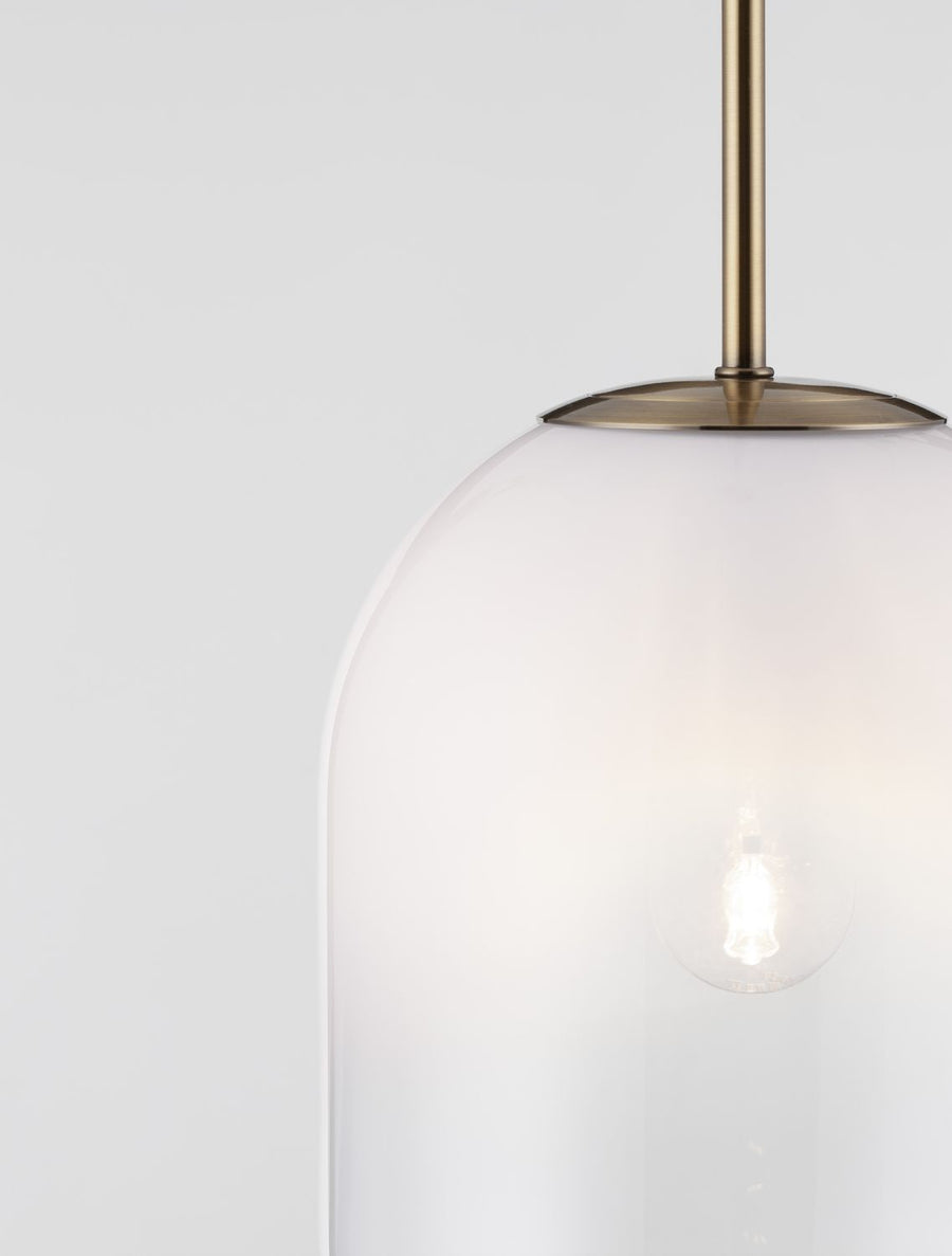 Gros plan sur la fixation dorée et le sommet du diffuseur en verre translucide.