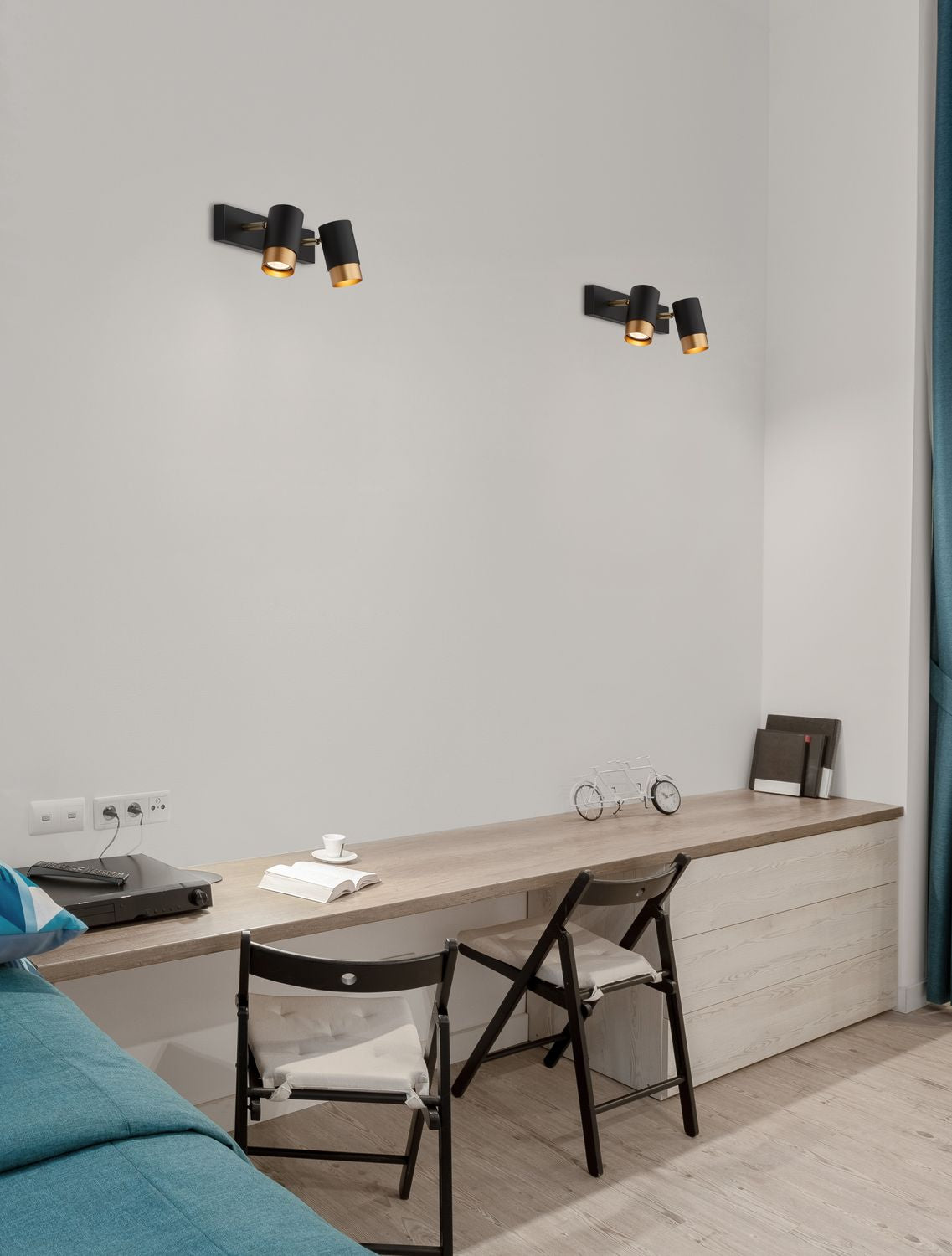Mise en ambiance de deux luminaires noirs et dorés fixés au mur au-dessus d'un bureau
