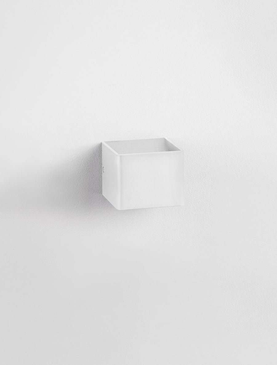Applique blanche carrée fixée sur un mur blanc, vue de trois quarts