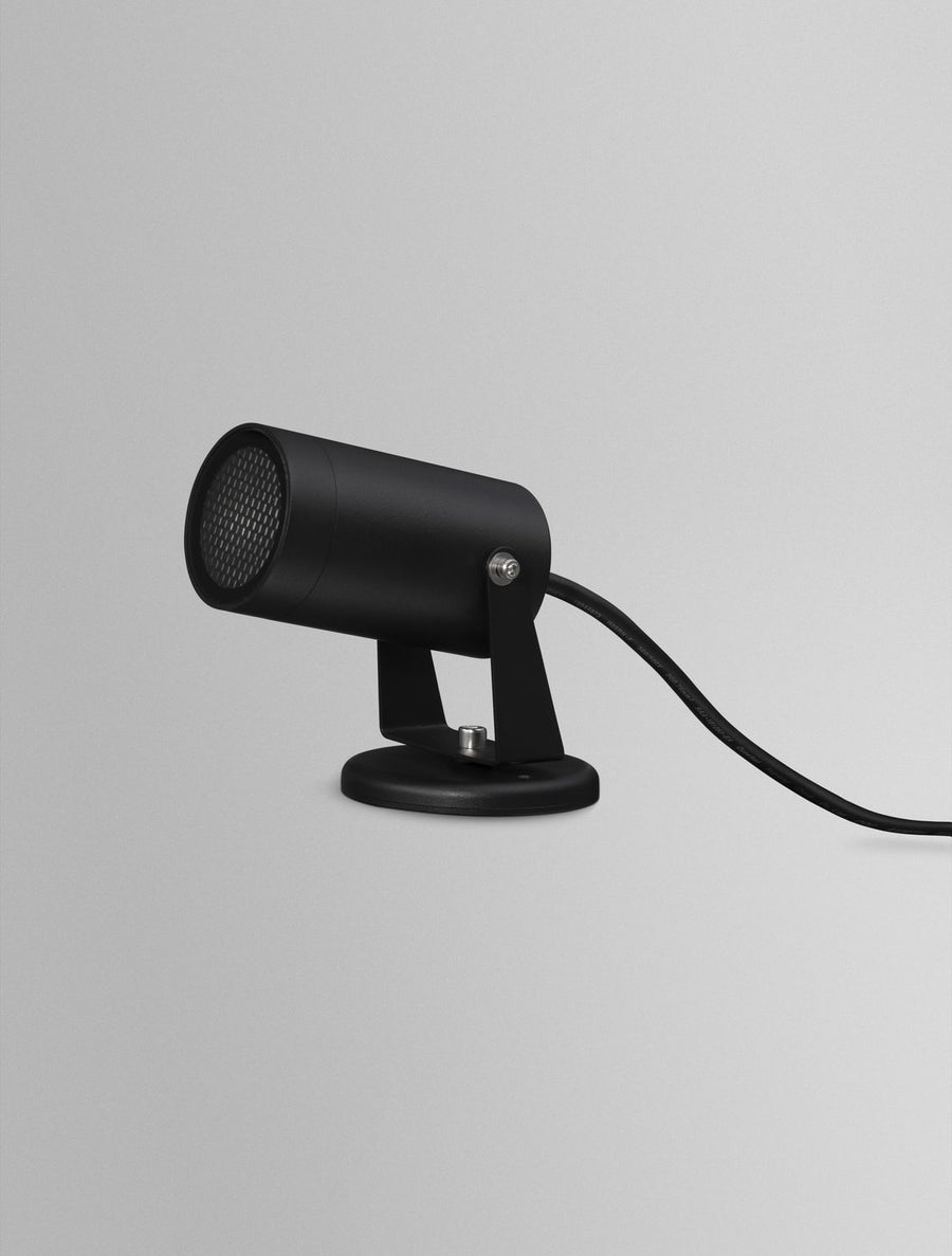 Projecteur noir vu de biais avec son câble d'alimentation apparent