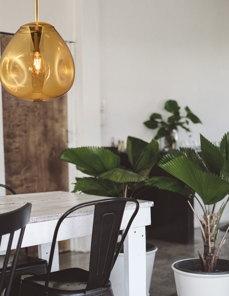 Suspension en verre doré allumée au-dessus d'une table blanche en salle à manger