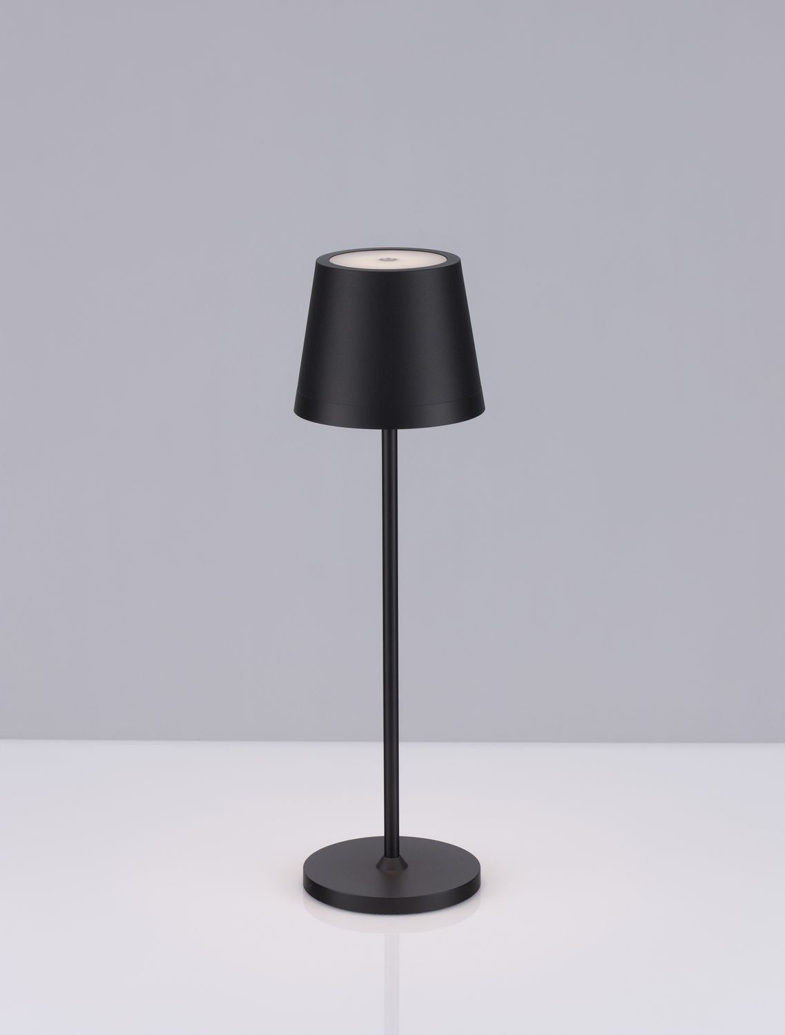 Présentation du luminaire noir sur fond gris clair, abat-jour conique et piètement fin.