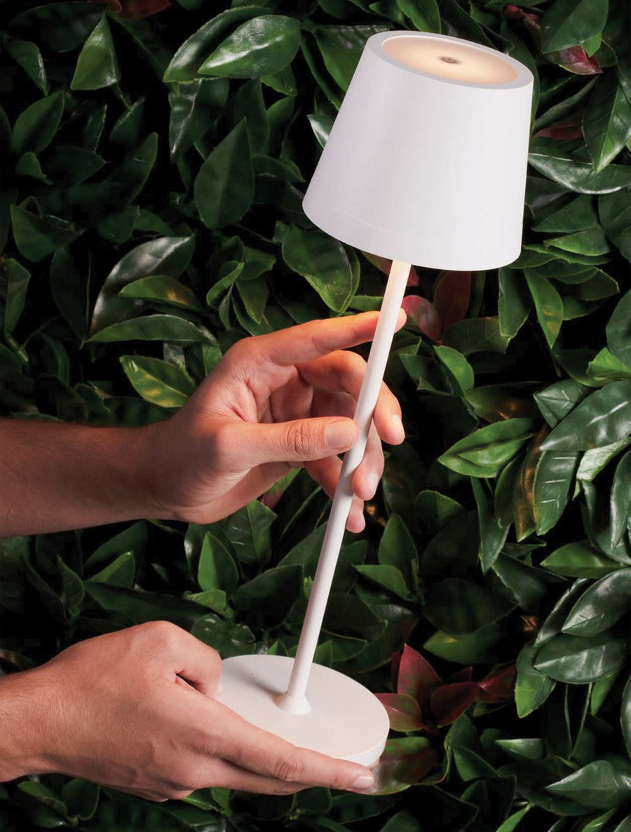 Mains tenant la lampe portative, détail du dessus et de l'interrupteur intégré