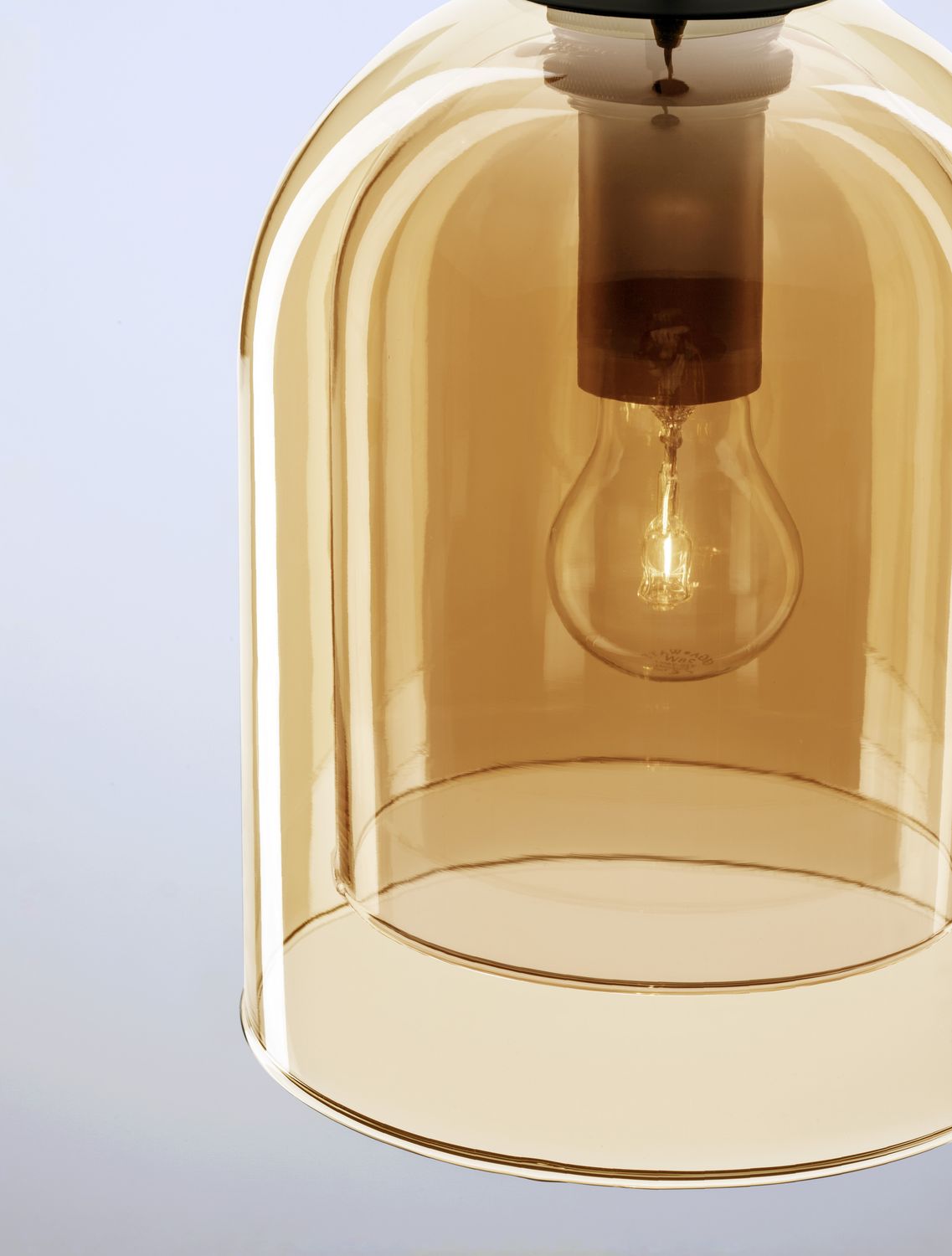 Gros plan sur l'abat-jour en verre ambré et l'ampoule allumée à l'intérieur
