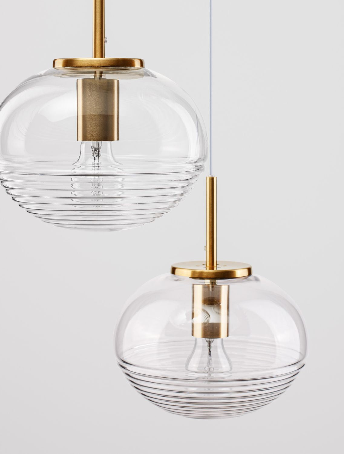 Gros plan sur deux globes en verre strié et leurs douilles dorées brossées