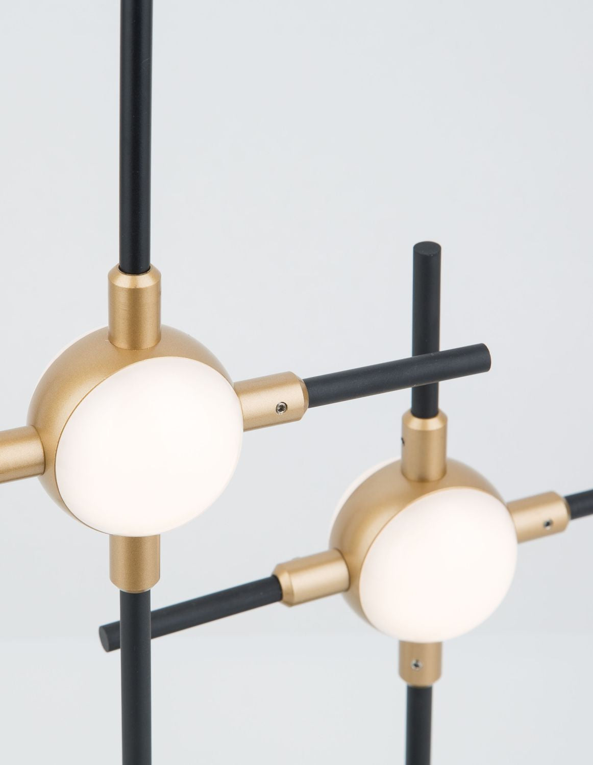 Gros plan sur deux globes blancs, raccords dorés et tiges noires croisées