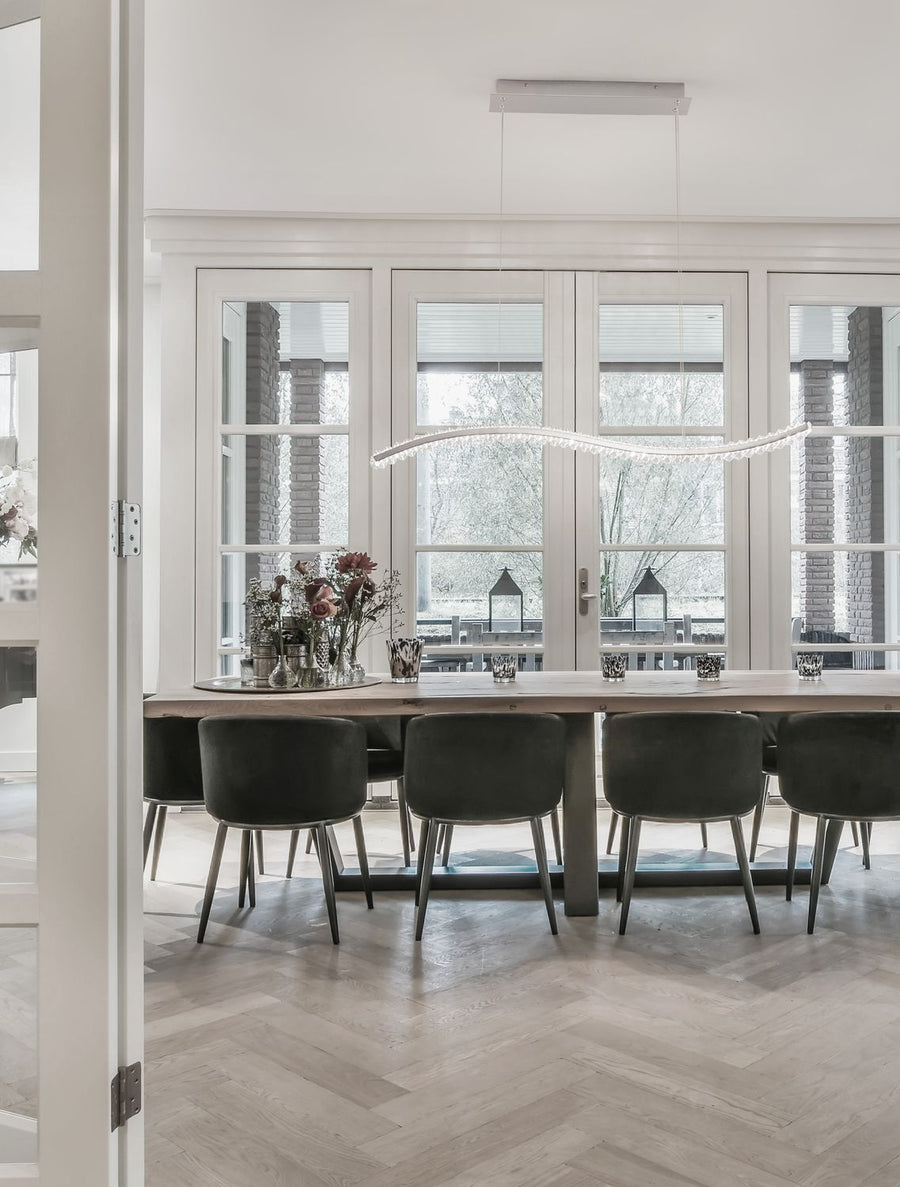 Suspension ondulée éclairée au-dessus d'une table de salle à manger claire et moderne
