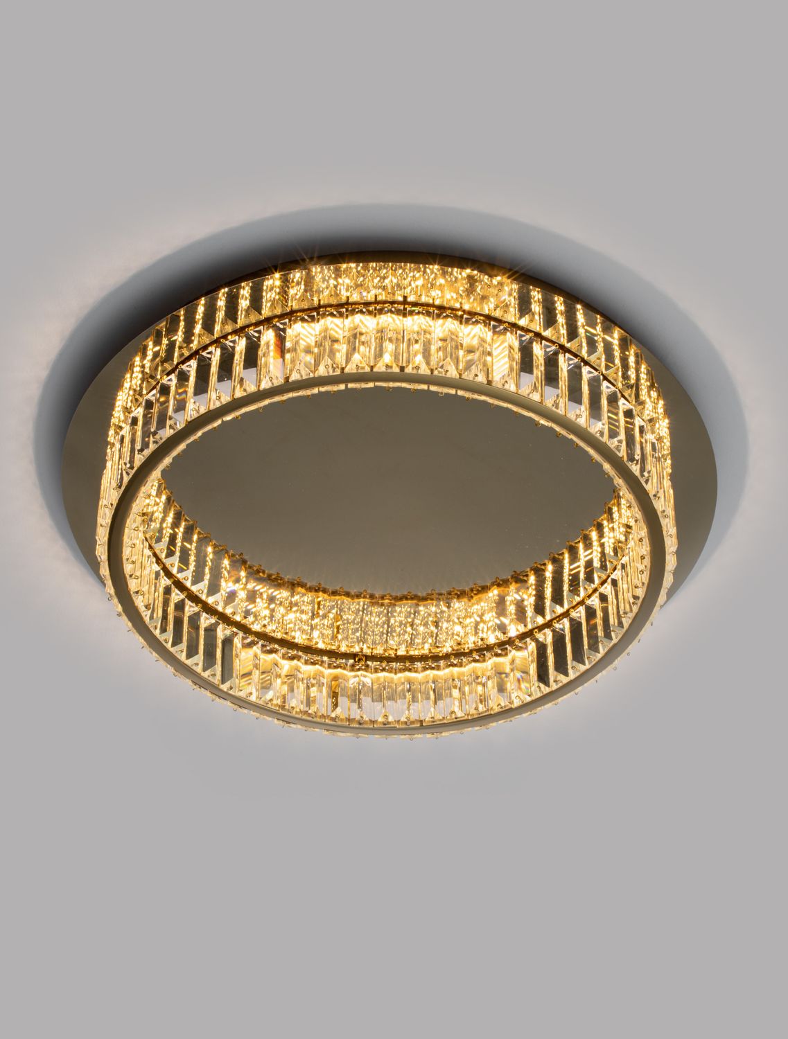 Gros plan du plafonnier illuminé montrant les tiges de cristal et la lumière chaude