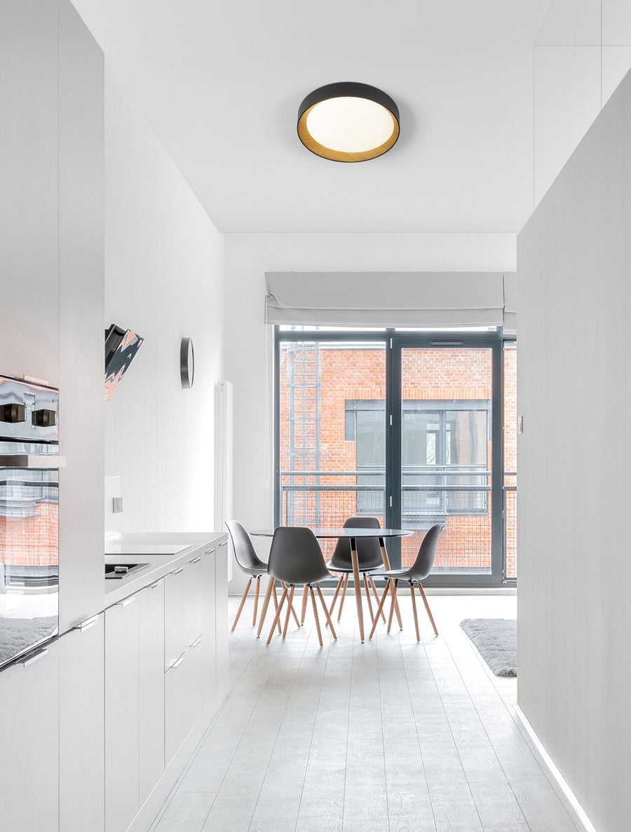 Plafonnier circulaire noir et bois installé au plafond d'une cuisine blanche moderne