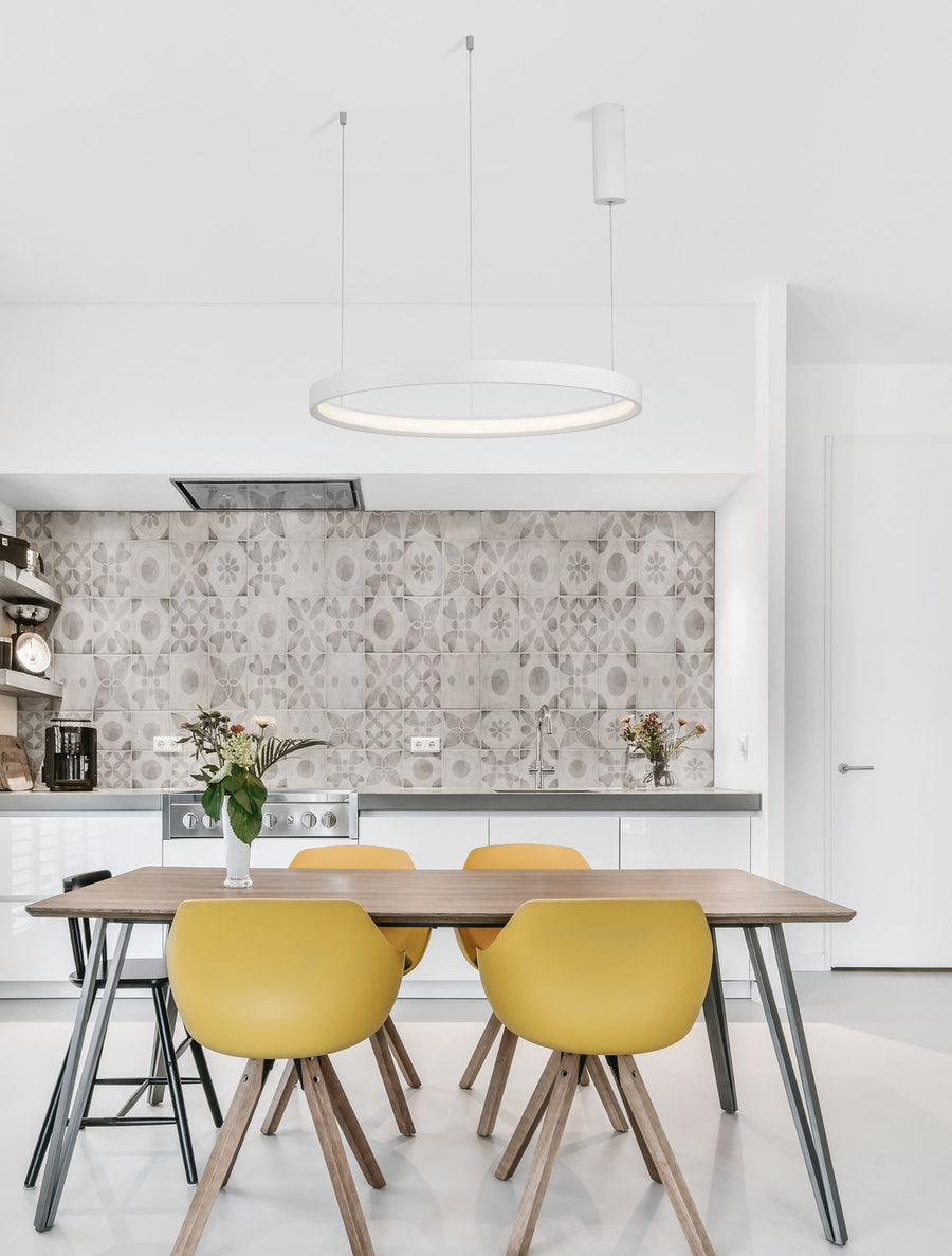 Suspension anneau blanc installée au-dessus d'une table de cuisine aux chaises jaunes