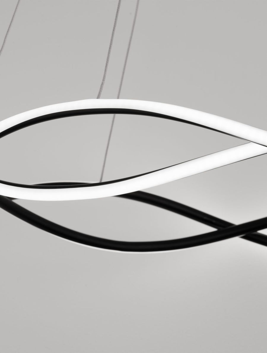 Zoom sur la boucle blanche éclairée croisant la structure noire mate du luminaire.