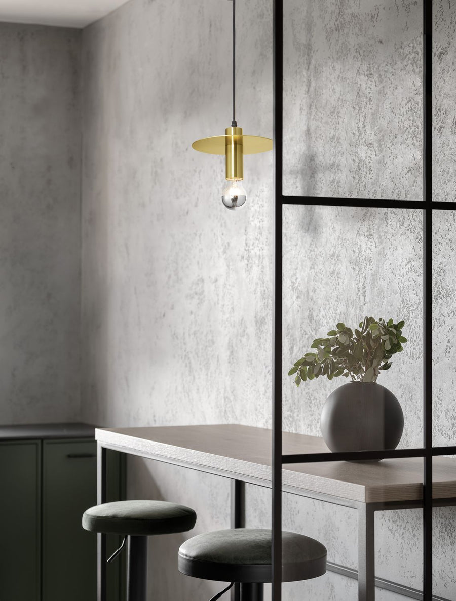 Suspension dorée suspendue au-dessus d'une table haute avec tabourets et plante
