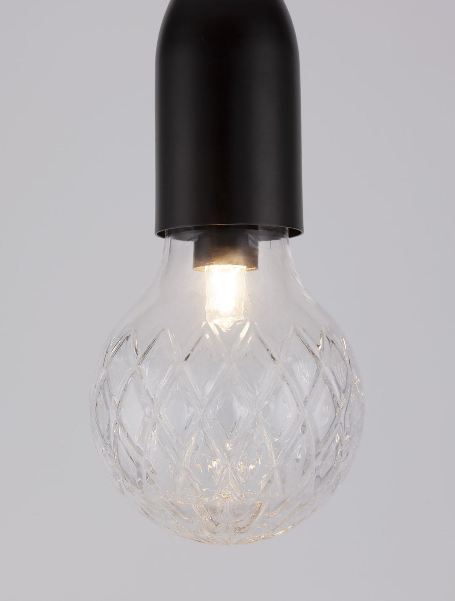 Détail de l'ampoule allumée, lumière chaude traversant le verre facetté