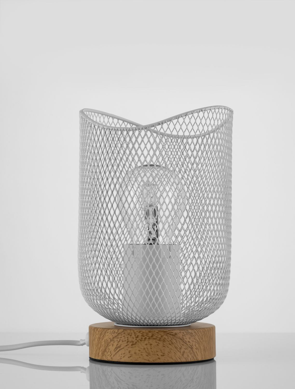 Lampe à poser blanche en maille métallique, socle en bois rond et câble blanc sur table.