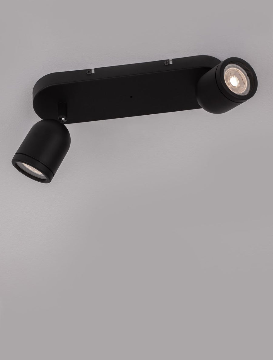 Détail d'un spot allumé sous la base noire mate, lumière chaude