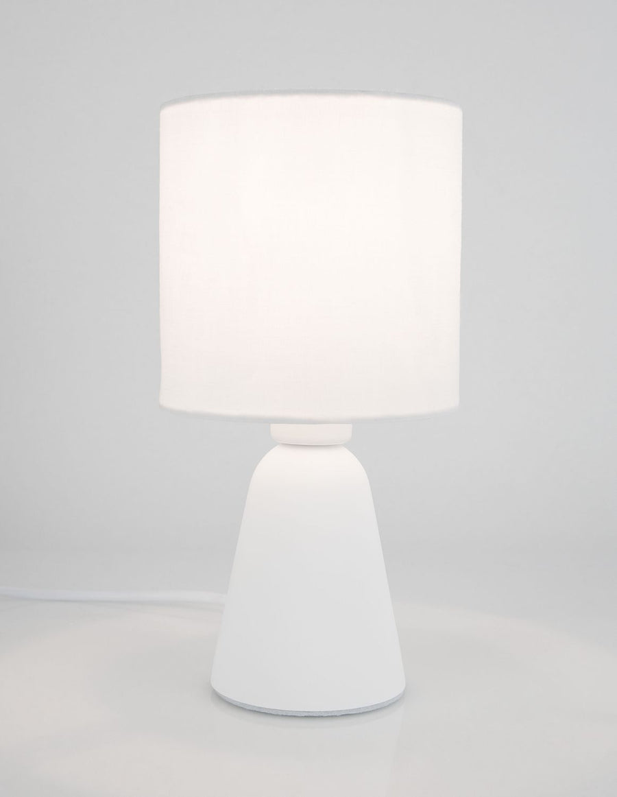 Lampe allumée dans une pièce claire, câble blanc visible au sol