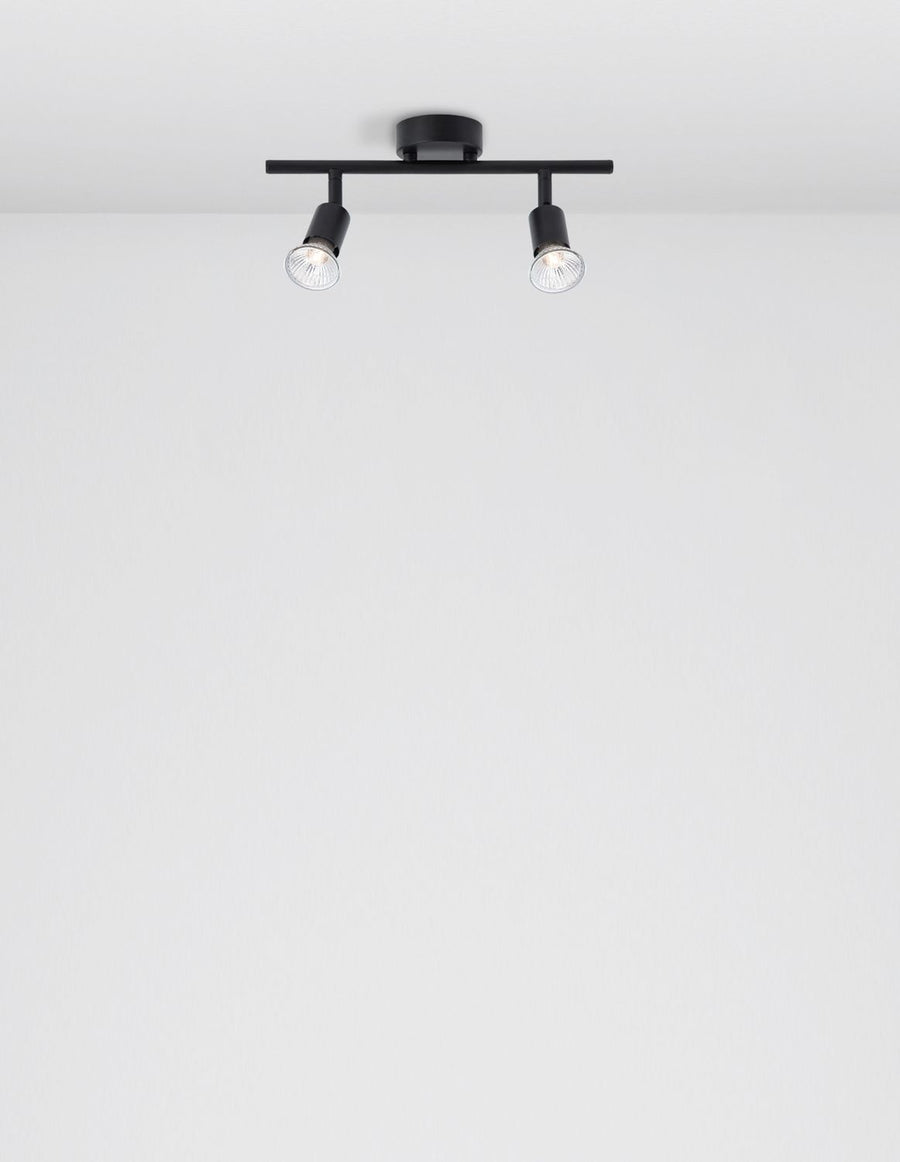 Vue de dessous du plafonnier noir fixé au plafond blanc, spots allumés