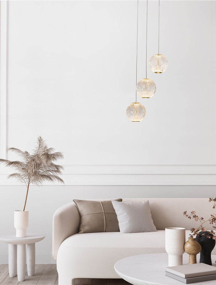 Suspension à trois globes en verre texturé éclairant un salon au mur blanc