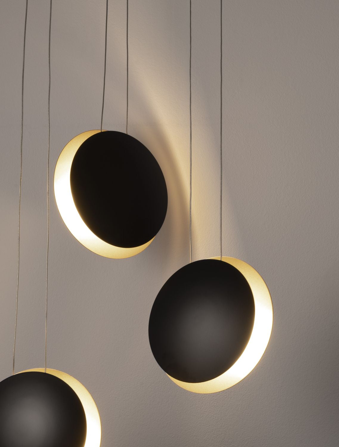 Luminaire allumé, halo doré projeté sur le mur derrière les disques noirs