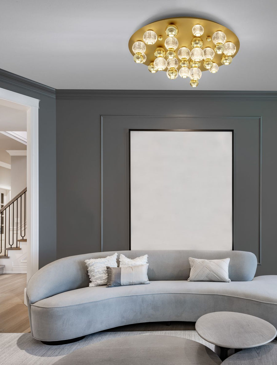 Plafonnier doré installé au plafond d'un salon gris avec canapé courbe