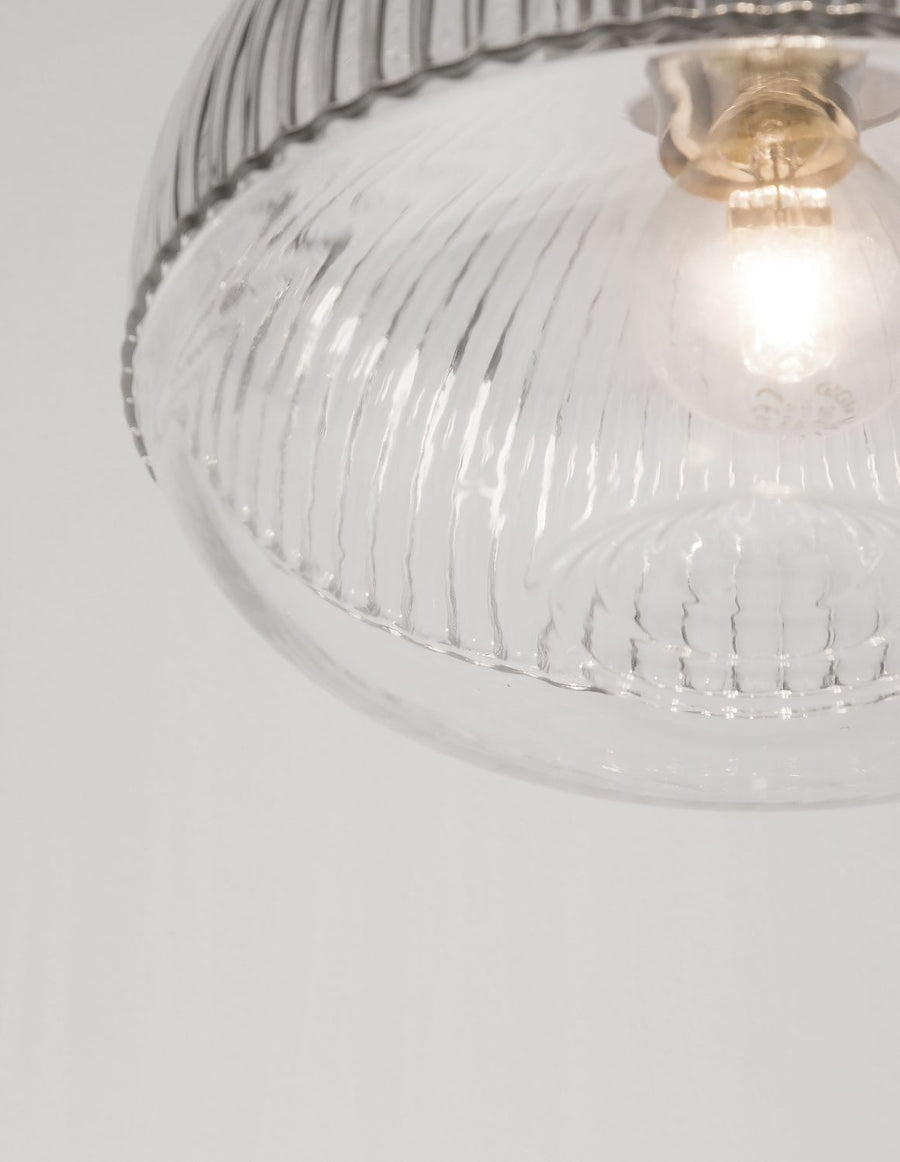 Vue rapprochée de l'ampoule allumée sous le verre transparent nervuré.