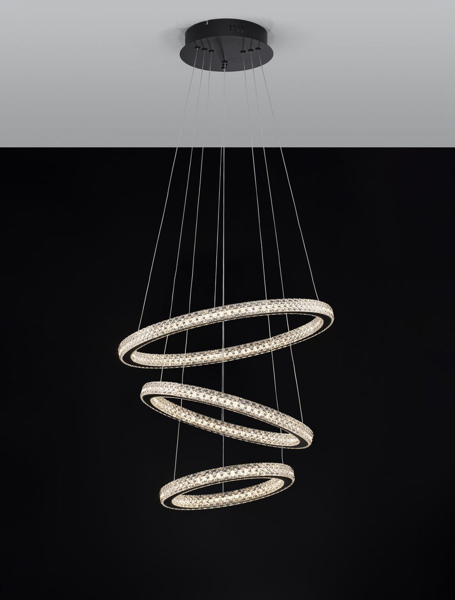 Suspension éclairée sur fond noir, anneaux lumineux et câbles apparents