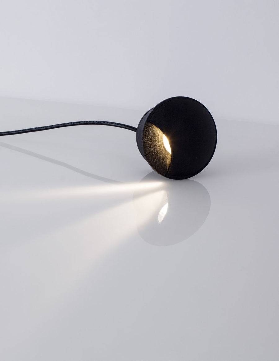 Luminaire allumé projetant un faisceau lumineux diffus sur une surface claire