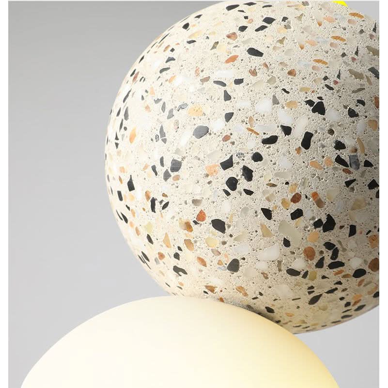 Détail rapproché du globe opalin et de la sphère mouchetée sous lumière chaude