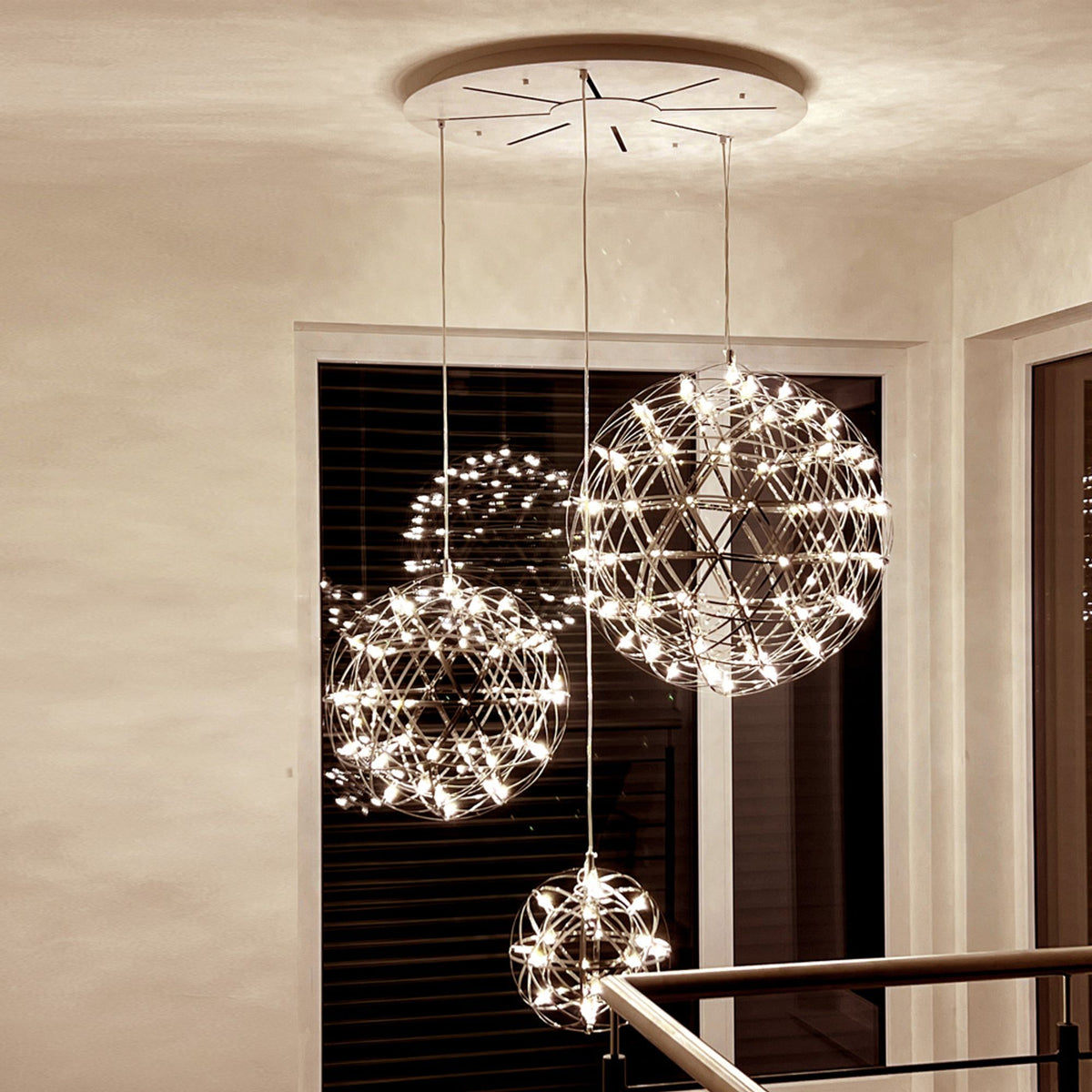 Trois globes lumineux de diamètres croissants devant une fenêtre sombre, la nuit