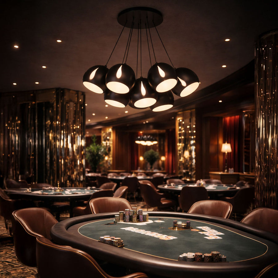 Modèle noir mat installé dans un casino, grappe de globes lumineux au-dessus des tables de jeu