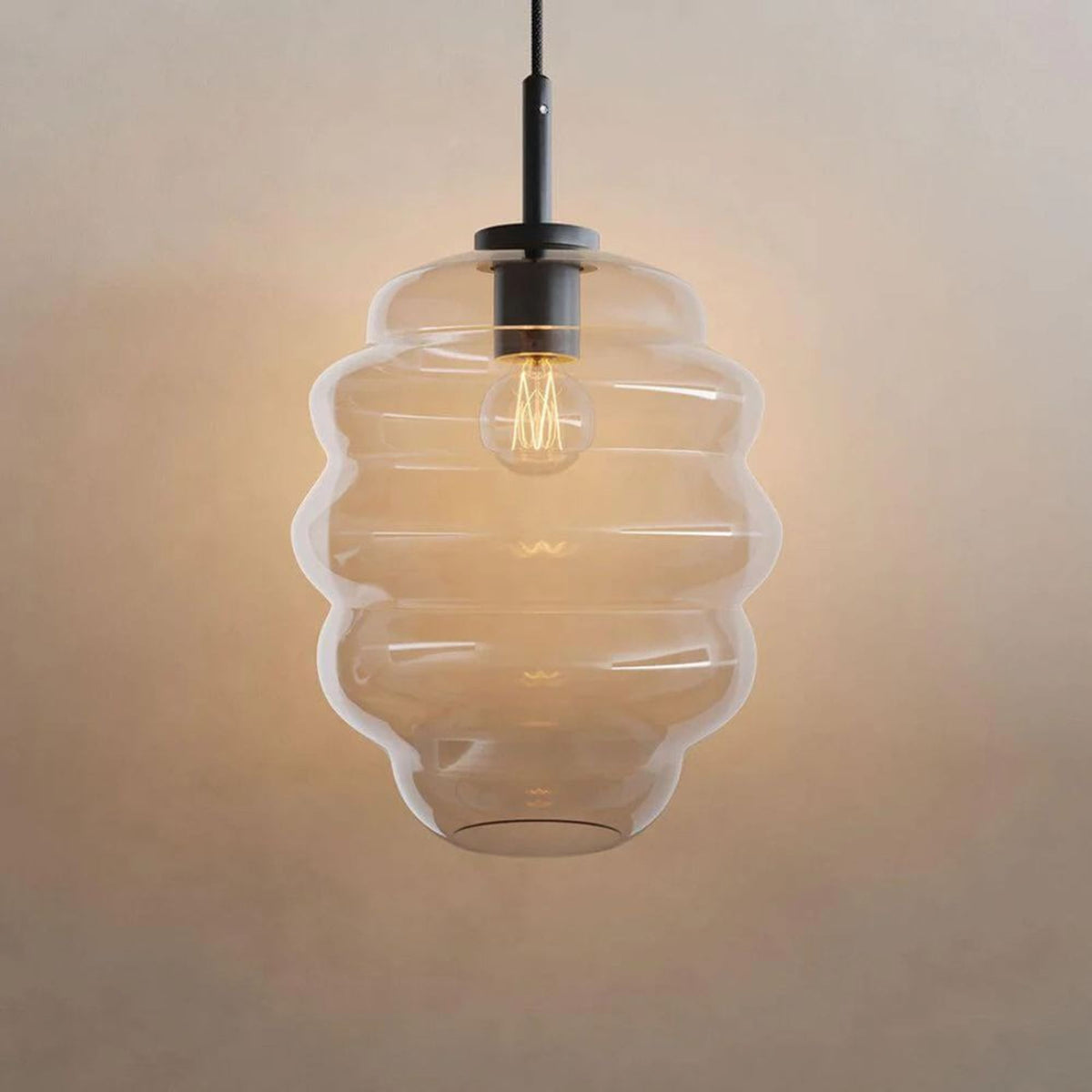 Verre fumé strié vu de face, ampoule filament allumée sur fond beige uni.