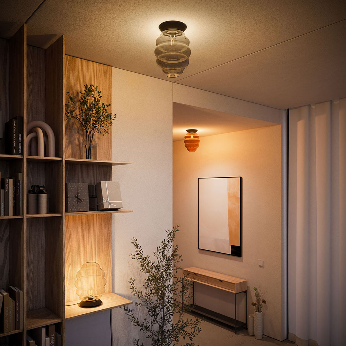 Mise en ambiance dans un intérieur avec étagère, tableau et deux plafonniers allumés.