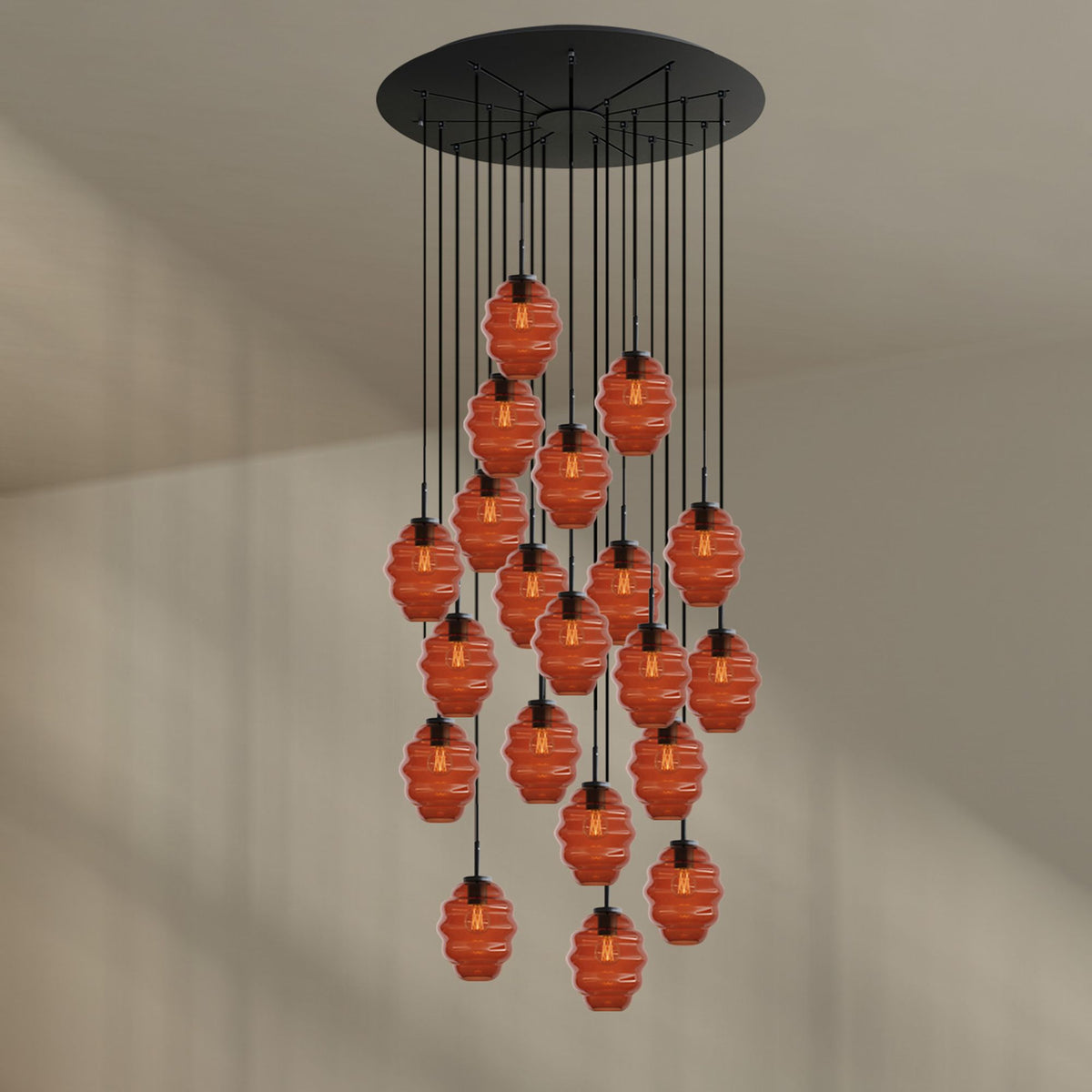 Vue de face sur fond clair, vingt verres orange suspendus à câbles noirs
