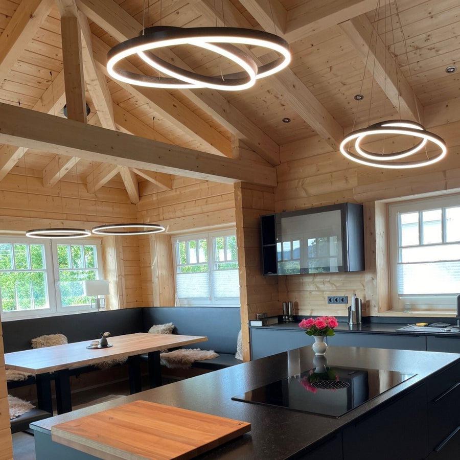 Anneaux noirs allumés au-dessus d'un îlot de cuisine dans un chalet en bois