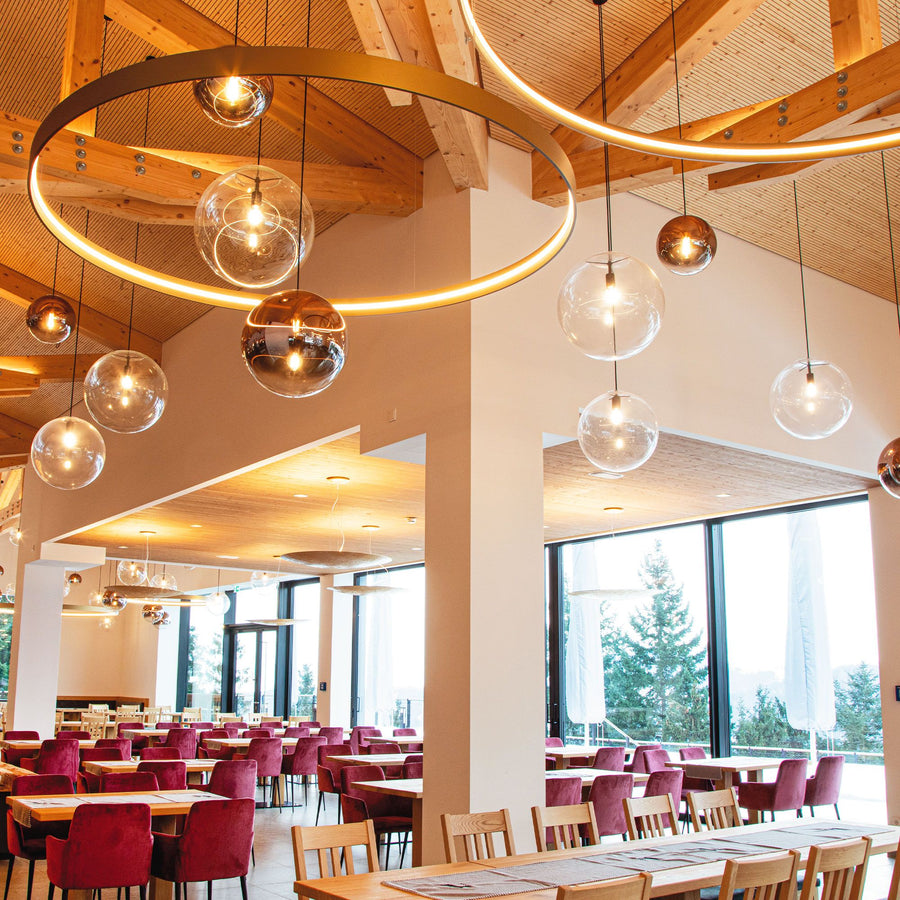 Anneau lumineux et globes de verre suspendus dans une salle de restaurant en bois