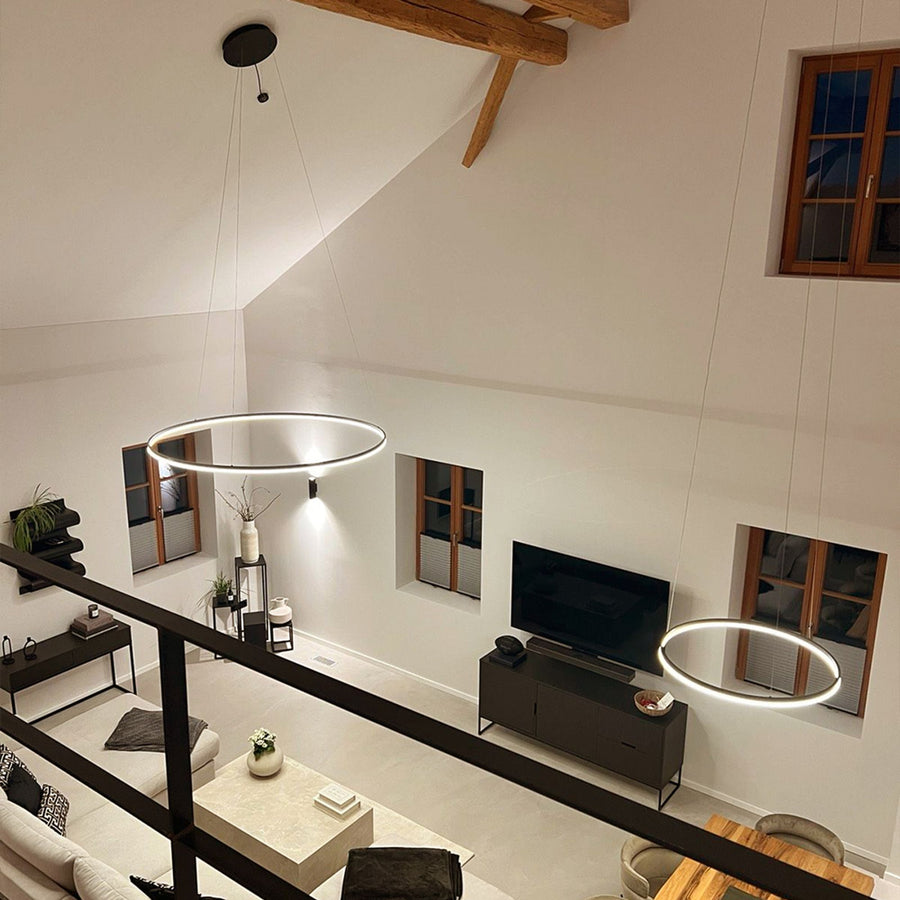 Deux anneaux lumineux suspendus dans un séjour à double hauteur
