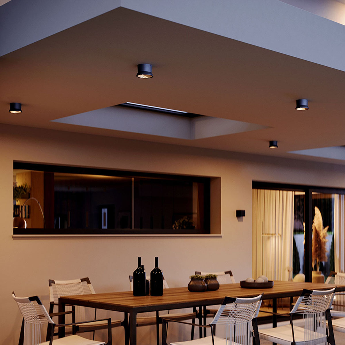 Ambiance terrasse couverte avec spots noirs au-dessus d'une table à manger en bois