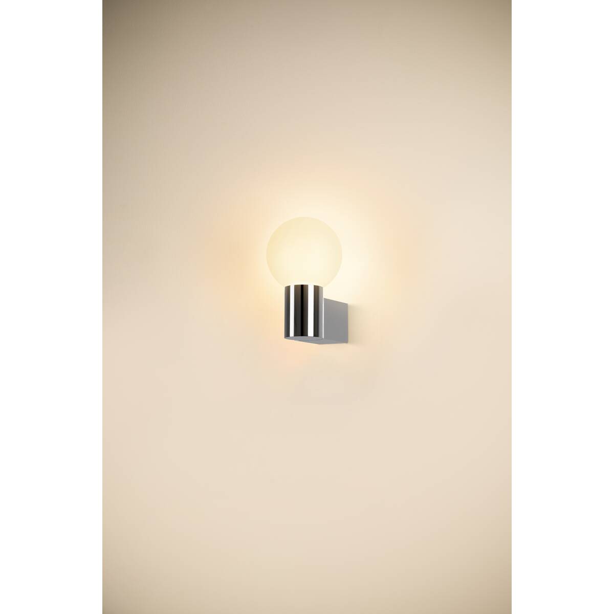 Applique murale allumée fixée sur un mur beige, diffusant une lumière chaude